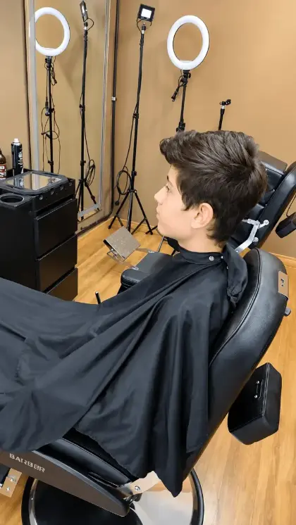 Cliente jovem na cadeira da Barbearia Milenitos